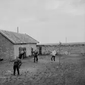 Familjegrupp fyra personer som spelar tennis. Bostadshus.
Hallebys resa.