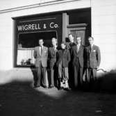 Grupp sex män, personalen.Byggnad i bakgrunden.Wigrell & Co.