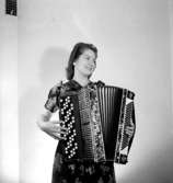 En kvinna med musikinstrument (dragspel).
Fröken Wettner