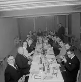 Rumsinteriör, grupp vid bordet. Personalklubben uppvaktar Olle Carlberg.
Örebro Kexfabrik.