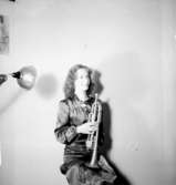 En kvinna med musikinstrument (trumpet).
Thory Bernhard