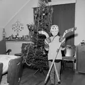 Rumsinteriör, en pojke i ishockeydräkt vid julgranen.
Hasse