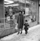 Konsum, exteriör, skyltfönster.En kvinna och en liten flicka.