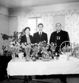 Rumsinteriör, familjegrupp tre personer.
Fredelius födelsedag.