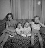 Rumsinteriör, fyra barn i soffan.Fru Blomberg