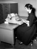 Kontorsinteriör, en kvinna vid skrivmaskinen.
Wigrell & Co.