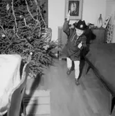 Rumsinteriör med julgran, en liten pojke.