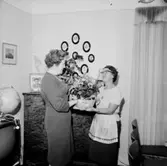 Rumsinteriör, två kvinnor. Personalklubben uppvaktar Dagmar Larsson på 60-årsdagen.
Örebro Kexfabrik.