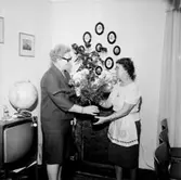 Rumsinteriör, två kvinnor. Personalklubben uppvaktar Dagmar Larsson på 60-årsdagen.
Örebro Kexfabrik.