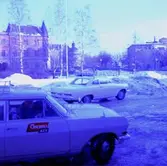 Personbil, en man i bilen. Örebro Kexfabrik.
Byggnader i bakgrunden, bl.a. Örebro Slott.