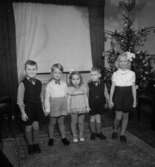 Rumsinteriör med julgran, fem barn.
Ulfgren