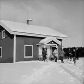 Skidåkning, sex personer.
Envånings byggnad.