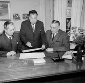 Normans bilfirma, kontorsinteriör, tre män.
Beställare: K&K, Stockholm.