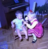 Rumsinteriör, två barn vid pianot.
Bertil Larsson