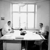 Ahréns Arkitektkontor, interiör, två män vid skrivbordet.
