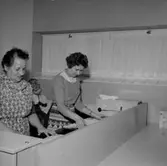 Konsum tvätt, interiör, strykning, två kvinnor och en pojke.