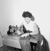 Interiör, en kvinna vid symaskinen.
