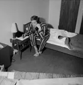 Sovrumsinteriör, en man i pyjamas vid telefonen, 