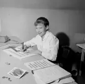 Kontorsinteriör, en kvinna vid skrivbordet.
Sedell Reklam.