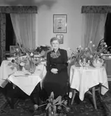 Rumsinteriör, en kvinna.
Fru Alm på födelsedagen.