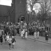 Konfirmation i Ljusnarsbergs kyrka, konfirmander, präst och människor utanför kyrkan.