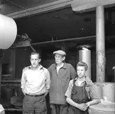 Verkstadsinteriör, grupp, tre män, avskedsfest för Kalle Wärnberg.