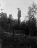 En man stående på hästryggen.