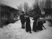 Vintermotiv. Bostadshus, en man och tre unga kvinnor framför huset.
Anders Johan Pettersson (givarens farfar) samt döttrarna.