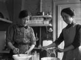 Köksinteriör, matlagning, två kvinnor.
Ester Pettersson och Olga Pettersson (givarens fastrar).