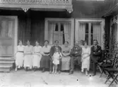 Bostadshus, släktgrupp tio personer framför huset, på gården Kungsgatan 33, Lindesberg.
Från vänster: Hildur Pettersson (givarens faster), tre ej namngivna personer, Martin Pettersson (givarens farbror), Kerstin Pettersson (givarens faster), Eva Sofia Pettersson (givarens farmor), Anders Johan Pettersson (givarens farfar), Ingrid Pettersson (givarens faster), ej namngiven man.