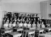 Klassrumsinteriör, 32 skolbarn med lärarinna.