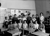 Klassrumsinteriör, 16 skolbarn med lärarinna.