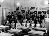 Klassrumsinteriör, 23 skolbarn med lärarinna.