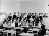 Klassrumsinteriör, 29 skolbarn med lärarinna.