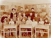 Stureskolan, klassrumsinteriör, klass 1A, sal 7.
20 skolbarn och lärarinna fröken Brita Dahlhielm.