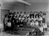 Olaus Petriskolan, klassrumsinteriör, 31 flickor med lärarinna fröken Olga Mossberg.
Klass 8a, sal 11 (hand.).