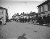 Militärtrupp på häst nedför Kungsgatan, Enköping, sett från torget mot öster, troligen 1908. Se mer under historik.