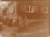 4/10 1925. Några personer utanför ett hus med fönsterluckor.
