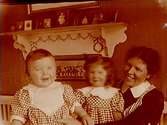 Rumsinteriör, en kvinna och två barn.
Gerda Thermaenius  (född Callmander) med barnen Sven och Maj.