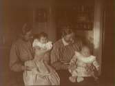 Rumsinteriör, två kvinnor och två barn.Från vänster Anna Gustavsson med dottern Anna-Greta och Edith Nerell med dottern Ingrid.Anna och Edith var döttrar till Edvard och Jenny Thermaenius. Bilden tagen i 