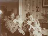 Rumsinteriör, två kvinnor och två barn.Från vänster Anna Gustavsson med dottern Anna-Greta och Edith Nerell med dottern Ingrid.Anna och Edith var döttrar till Edvard och Jenny Thermaenius. Bilden tagen i 