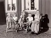 Gården Vänhem, Tvååker. Vid en vägg står trädgårdsmöbler. Där sitter barnen Henry, Rolf och Åke, Ulla och Gudrun (efternamn okänt).