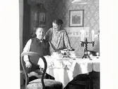 Fotografen Gerda Winqvist med sin (halv)bror Fredrik Winqvist på Annandag jul 1931 vid dukat bord med tända juleljus.