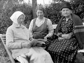 Tre kvinnor fotograferade sittande ute. Från vänster Charlotte Abrahamsdotter, Julia Lidholm och eventuellt Hilma eller Selma Linder.