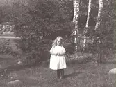 Barnporträtt. En flicka fotograferad ute i naturen. Namnet okänt.