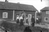 Bostadshus, familjegrupp sju personer framför huset.