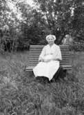 En kvinna sittande på en bänk.
Dalarna.