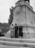 En man och två kvinnor framför Carl XV:s staty i Stockholm.