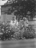 En pojke och en flicka utomhus. Bilden är tagen vid Margretehill i Norberg. Pojken är Lars (givarens) bror Anders och hans syster Karin som kallades Kajsa. Hon hade Downs syndrom. Karin föddes 1931 och dog 1938. Här verkar hon vara ca 2 år alltså kan bilden vara tagen ca 1933. Anders var 6 år då.