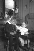 Rumsinteriör, en pojke och en flicka sitter vid ett litet bord.
Olof och hans syster Britta Andersson.